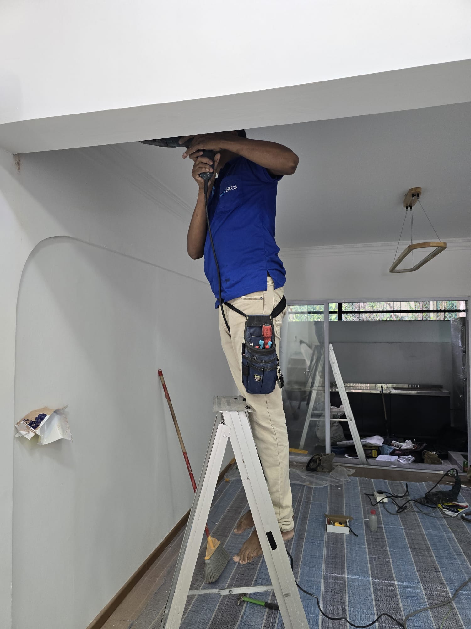 A1 Electrician worker drilling a ceiling point during an HDB installation
